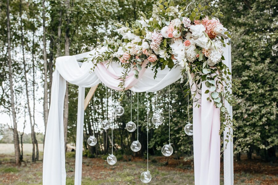 Decorating the arch with flowers and fabric for a wedding ceremony in nature